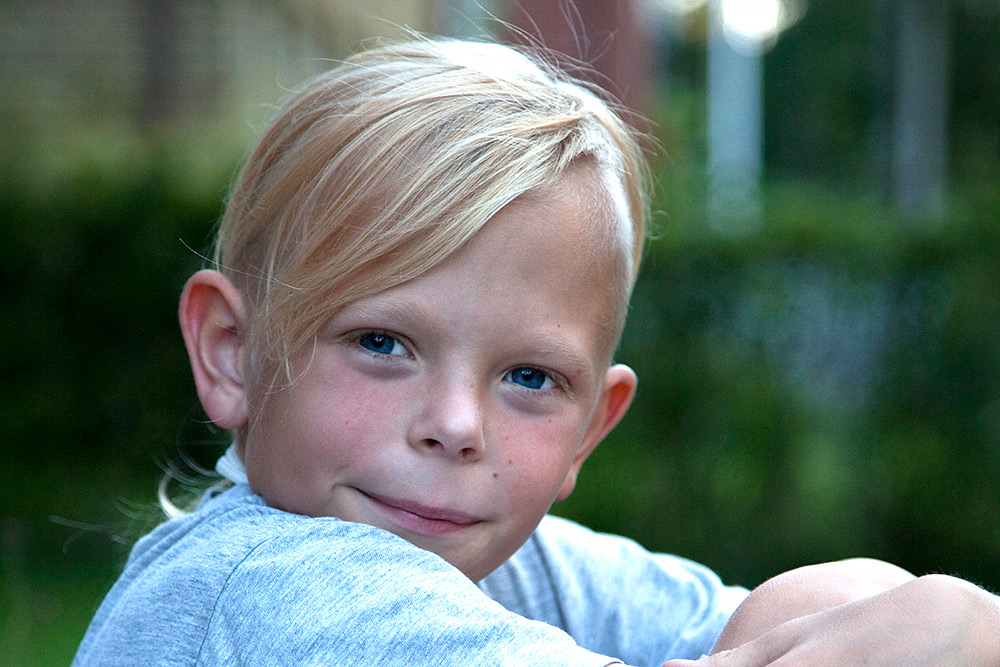 ung leende blåögd ljushårig svensk pojke med glimten i ögonen